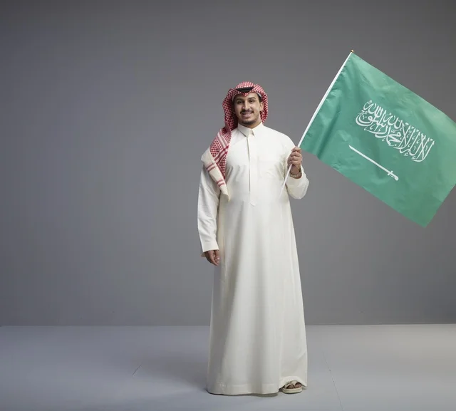 رجل سعودي يحمل علم المملكة العربية السعودية رجل سعودي يحمل علم المملكة العربية السعودية