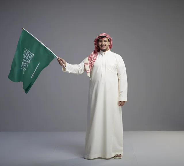 رجل سعودي يلوح بعلم المملكة العربية السعودية في استوديو