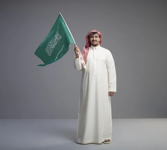 رجل سعودي يحمل العلم السعودي في الاستوديو