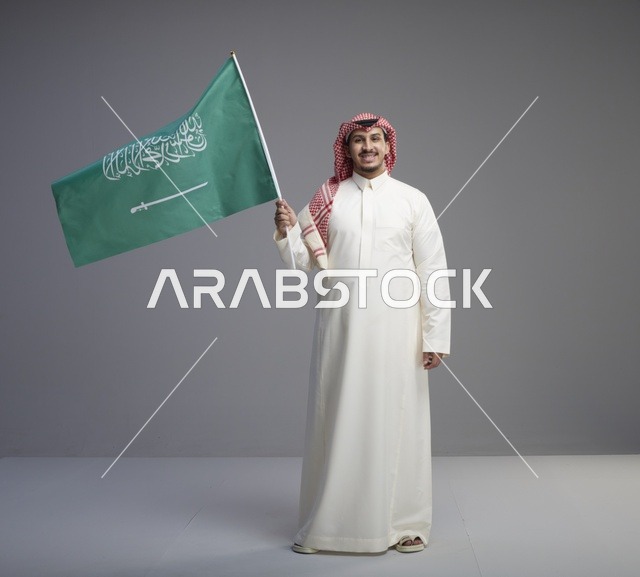 رجل سعودي يحمل العلم الوطني في استوديو تصوير