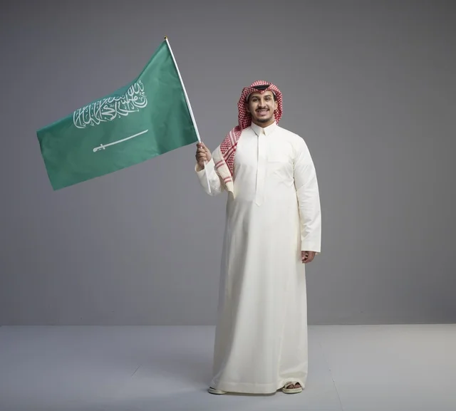 رجل سعودي يحمل العلم الوطني في استوديو تصوير