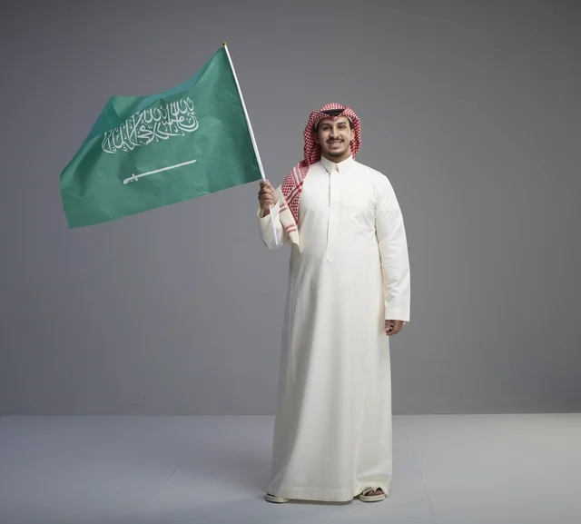 رجل سعودي يلوح بالعلم السعودي في تصوير استوديو