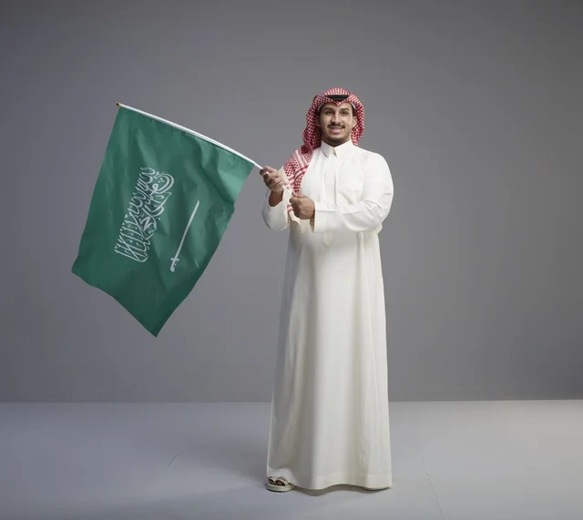رجل سعودي يحمل علم المملكة العربية السعودية في استوديو