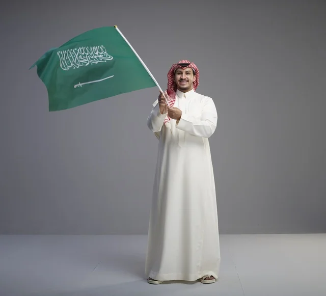 Saudi Man Holding National Flag in Studio Setting