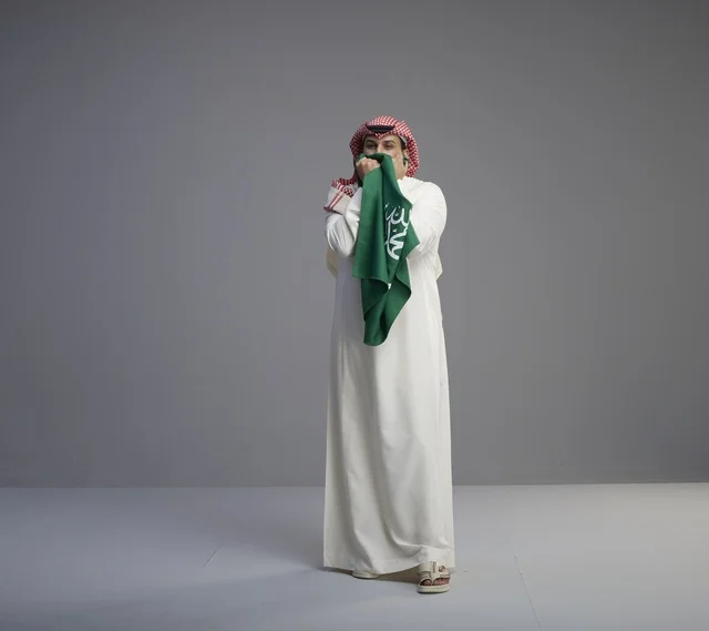 رجل سعودي يقبل العلم السعودي في استوديو