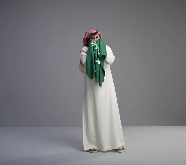 رجل سعودي يحمل العلم الوطني في الاستوديو
