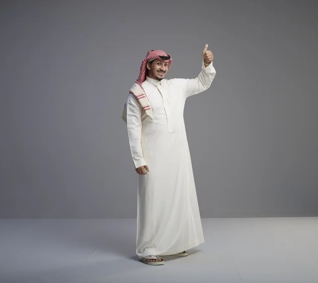 رجل سعودي بالزي التقليدي يشير بعلامة الإعجاب