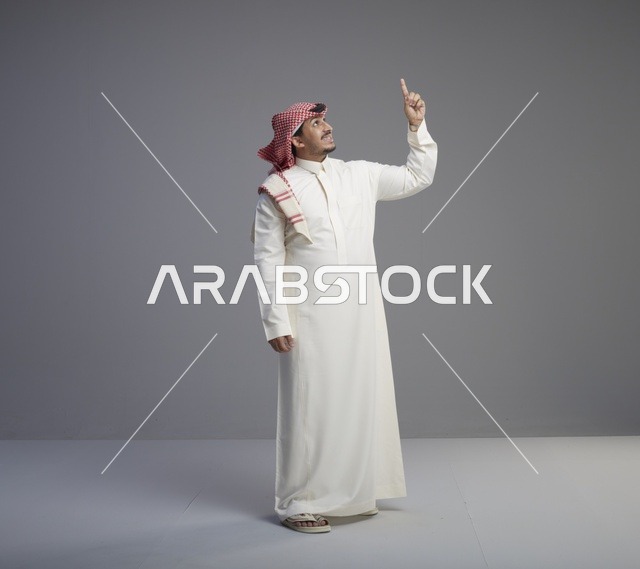 رجل سعودي بالزي التقليدي يشير للأعلى
