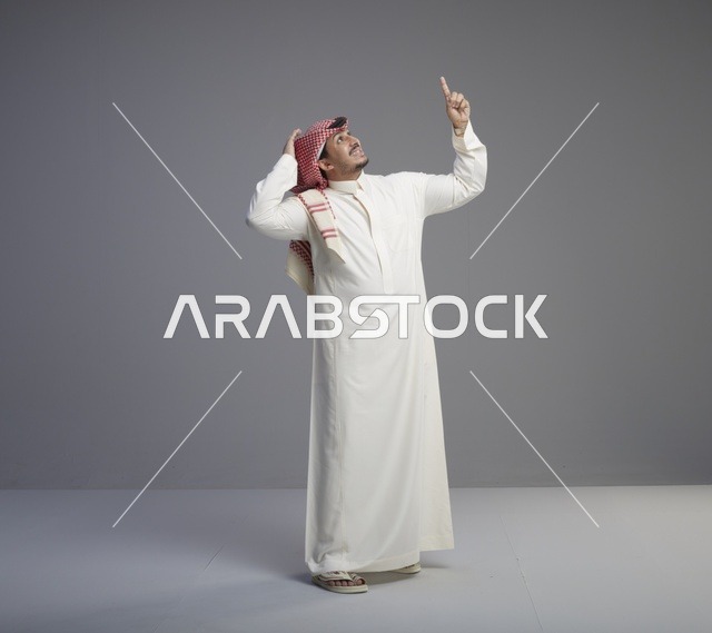 رجل سعودي بالزي التقليدي يشير إلى الأعلى