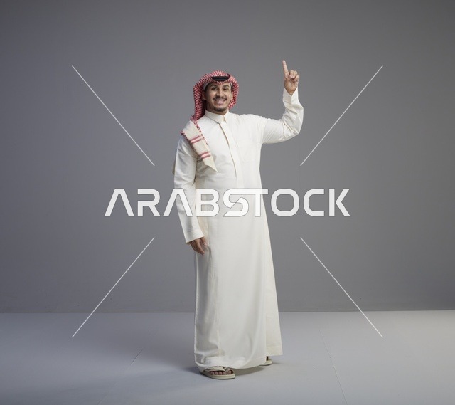 رجل سعودي يرتدي الثوب التقليدي ويشير للأعلى