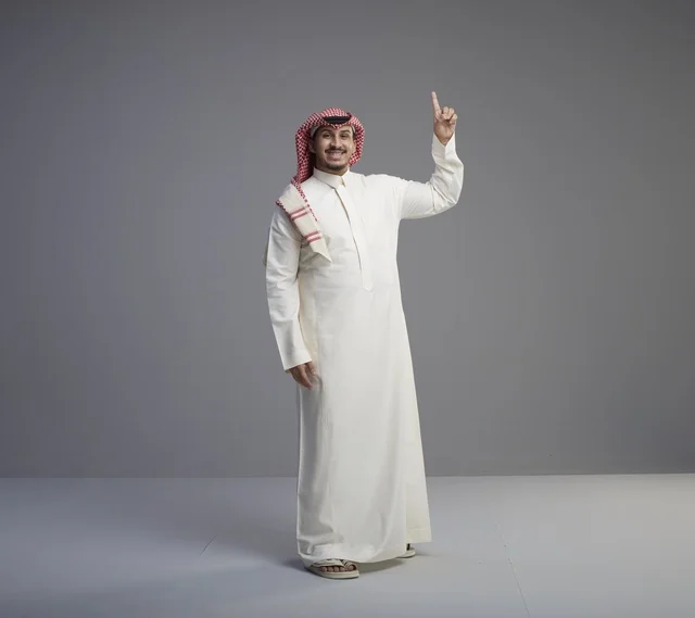 رجل سعودي يرتدي الثوب التقليدي ويشير للأعلى