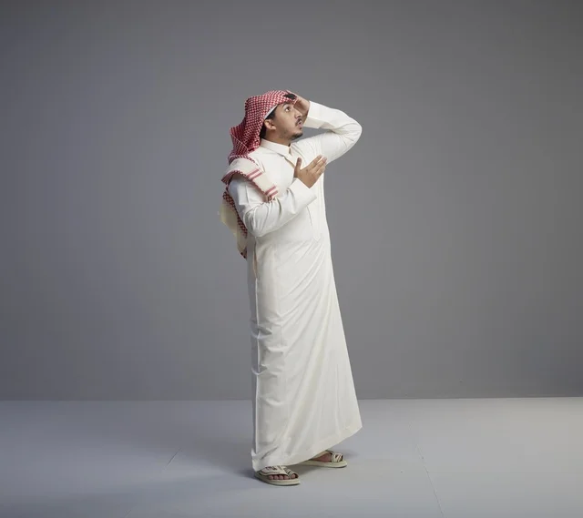 رجل سعودي بالزي التقليدي ينظر للأعلى في الاستوديو