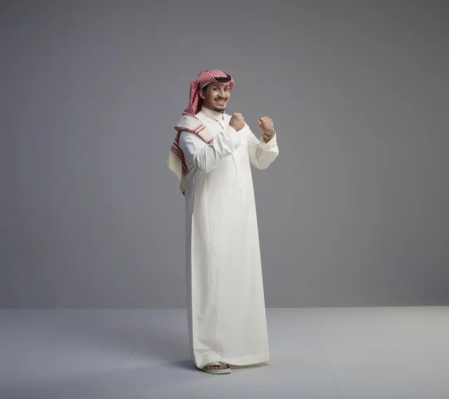 رجل سعودي بالزي التقليدي يحتفل بالنجاح في الاستوديو