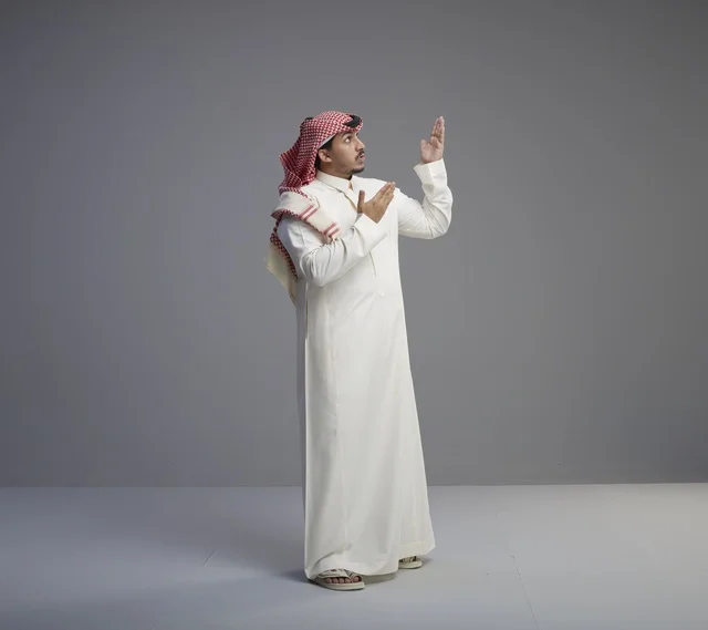 Saudi Man in Traditional Thobe Praying in Studio