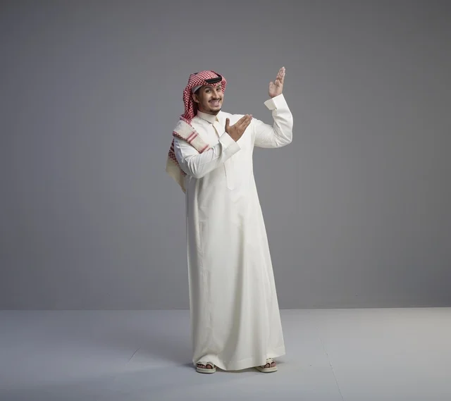 رجل سعودي بالزي التقليدي يشير بيده في استوديو