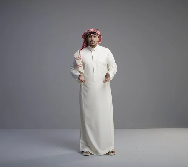 رجل سعودي متفاجئ بالزي التقليدي أمام خلفية رمادية