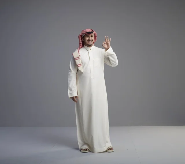 رجل سعودي بالزي التقليدي يشير بعلامة الموافقة