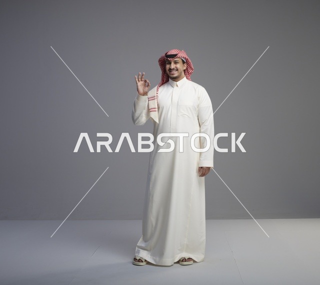 رجل سعودي بالزي التقليدي يشير بعلامة التمام