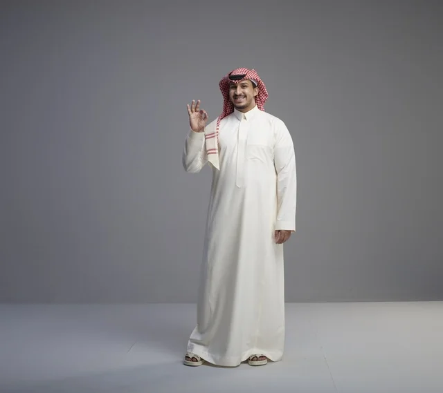 رجل سعودي بالزي التقليدي يشير بعلامة التمام