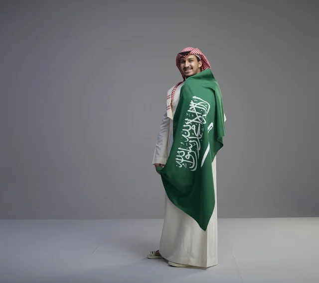 Saudi Man in Traditional Thobe Holding National Flag