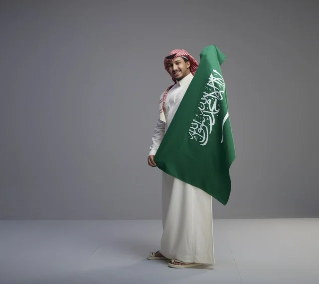 رجل سعودي يحمل العلم الوطني في الاستوديو