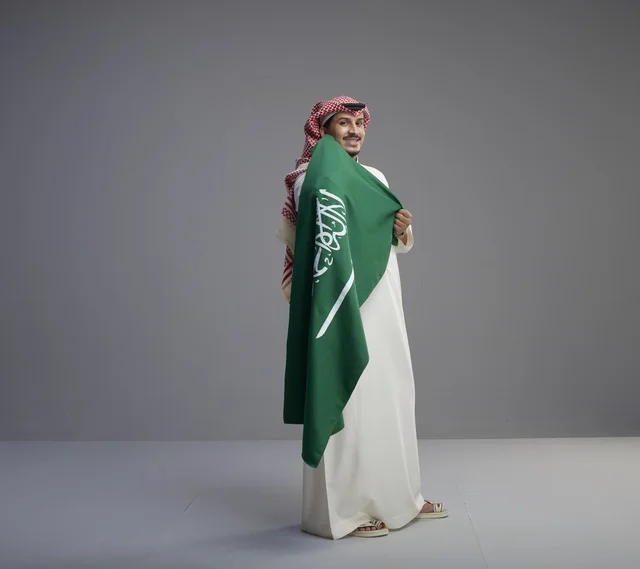 رجل سعودي يحمل علم المملكة العربية السعودية