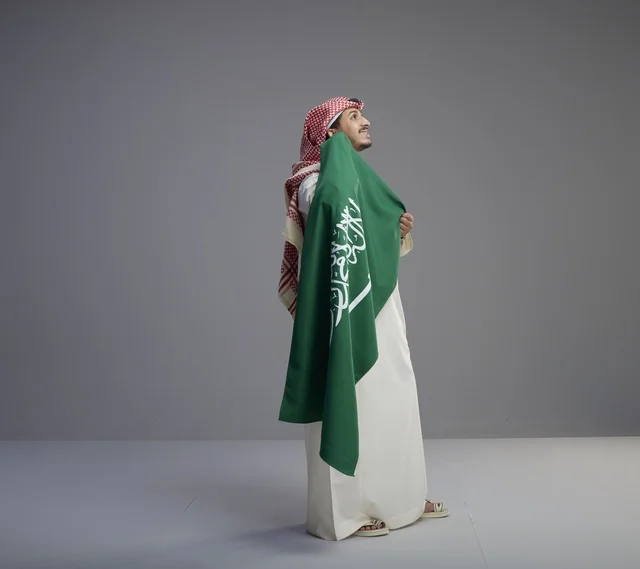رجل سعودي يحمل العلم الوطني السعودي في استوديو