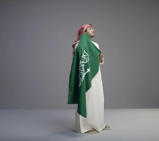 رجل سعودي يحمل علم المملكة العربية السعودية في الاستوديو