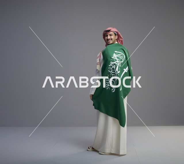 رجل سعودي يحمل العلم الوطني في استوديو