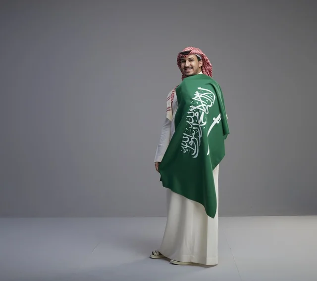 رجل سعودي يحمل العلم الوطني في استوديو