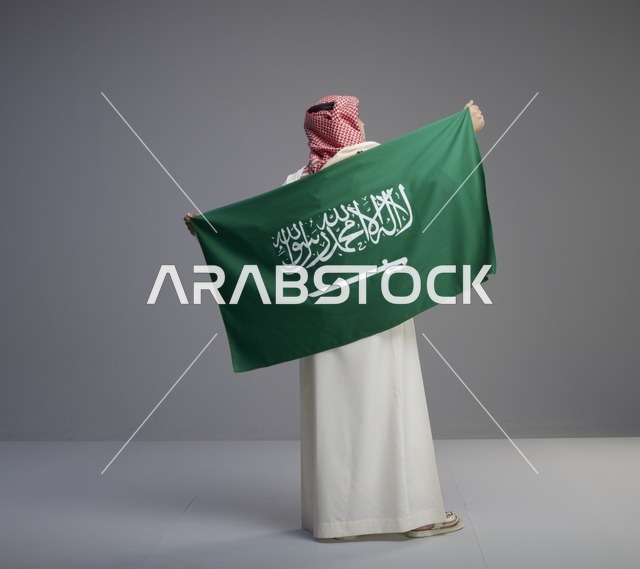 رجل سعودي يحمل علم المملكة العربية السعودية