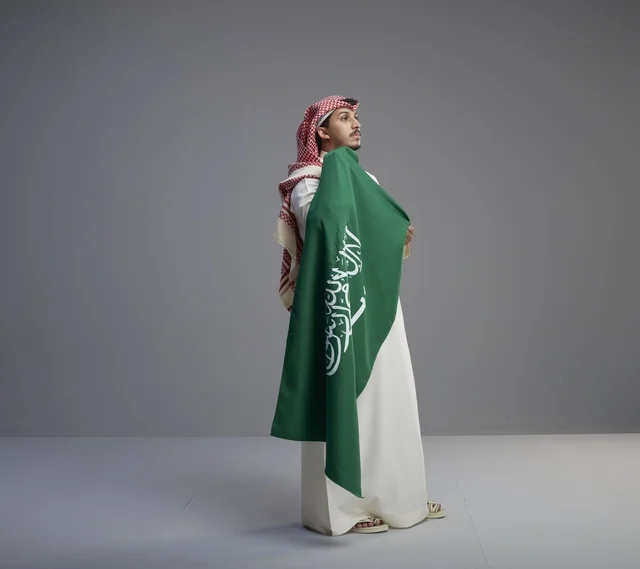 رجل سعودي يحمل العلم الوطني السعودي في استوديو