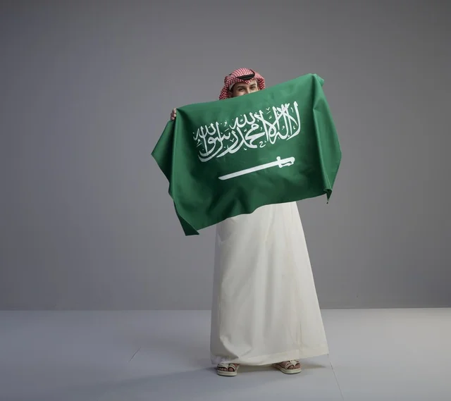 Saudi Man Holding National Flag in Studio Portrait