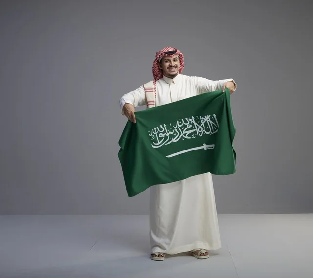 رجل سعودي يحمل علم المملكة العربية السعودية