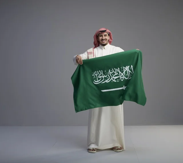 رجل سعودي يحمل العلم الوطني السعودي