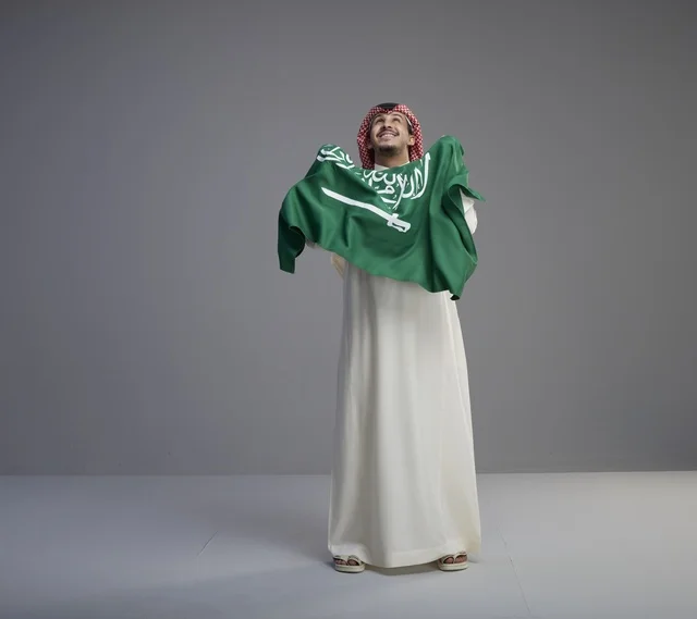 رجل سعودي يحمل العلم الوطني في استوديو