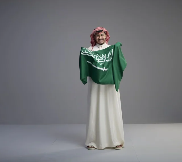 رجل سعودي يحمل العلم الوطني السعودي في الاستوديو