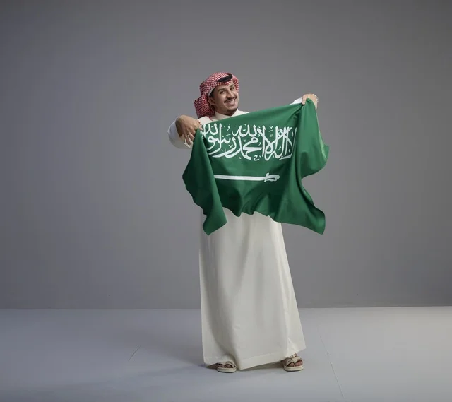 Saudi Man Holding National Flag in Studio Setting