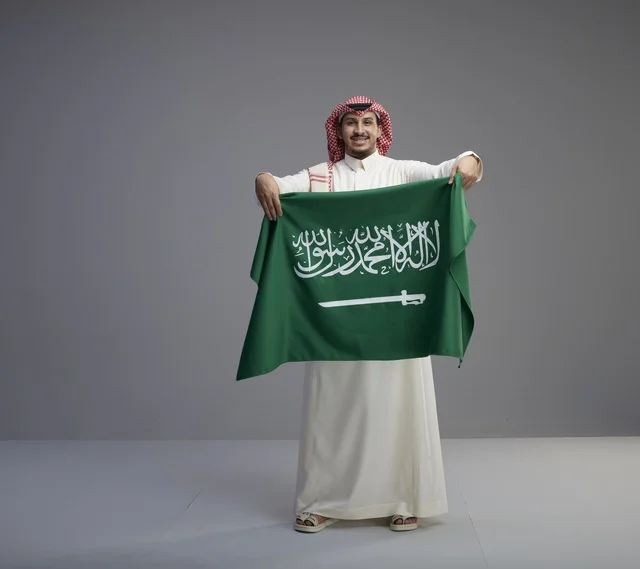 رجل سعودي يحمل العلم الوطني السعودي في الاستوديو