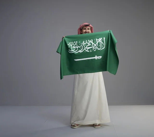 رجل سعودي يحمل العلم الوطني في الاستوديو