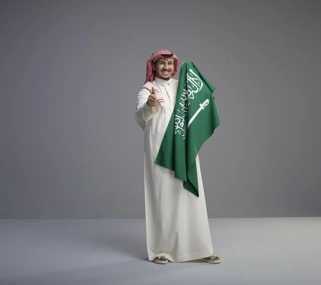 رجل سعودي يحمل العلم الوطني السعودي في الاستوديو