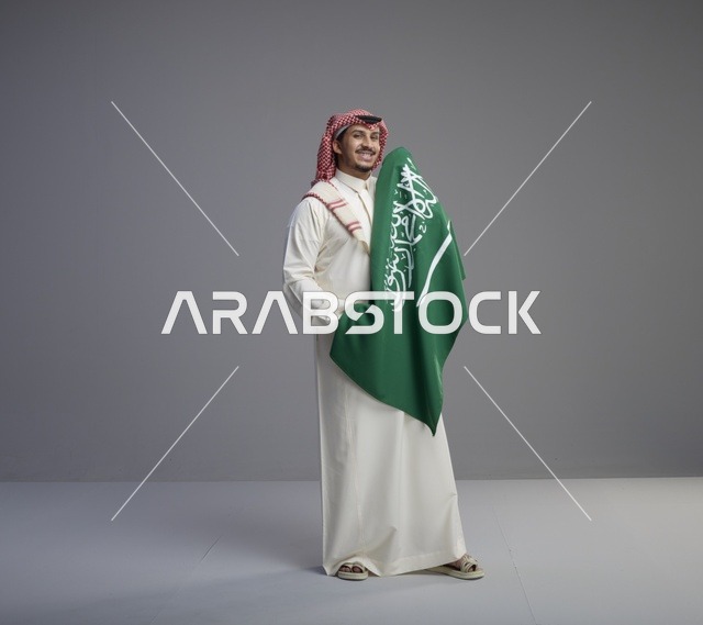 رجل سعودي يحمل العلم السعودي في الاستوديو