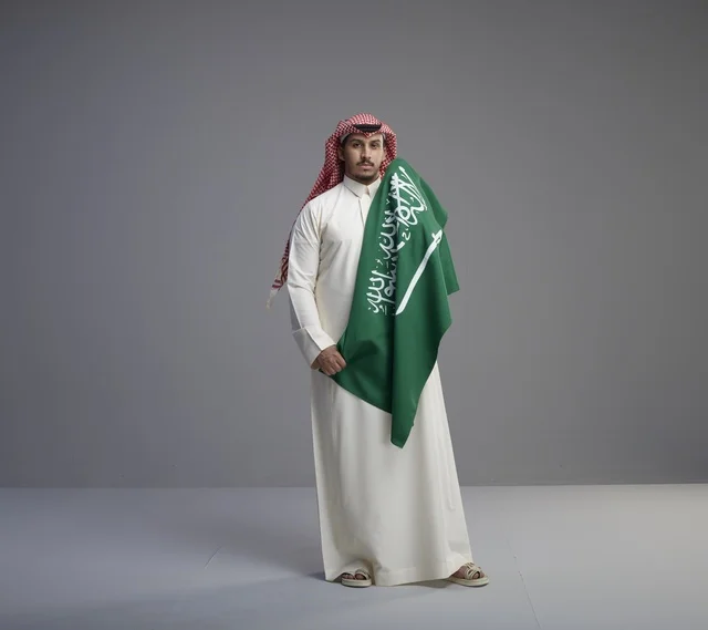Saudi Man Holding National Flag in Studio Background