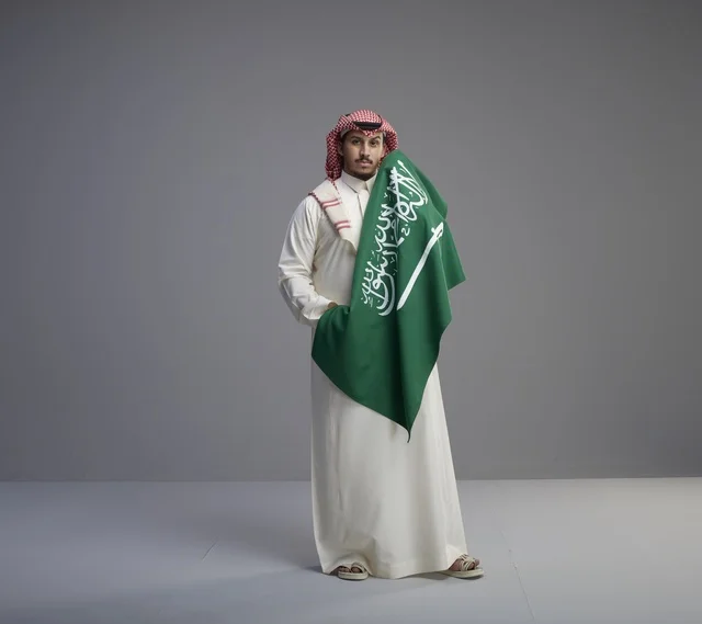 رجل سعودي يحمل العلم الوطني في الاستوديو