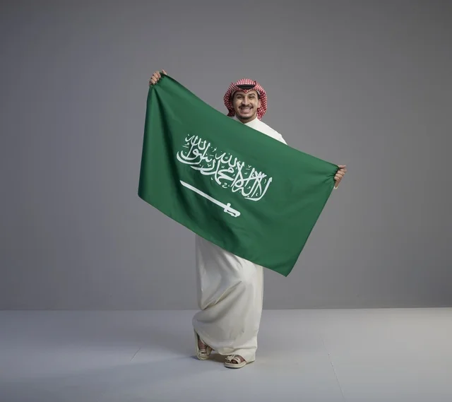 رجل سعودي يحمل العلم الوطني السعودي في الاستوديو
