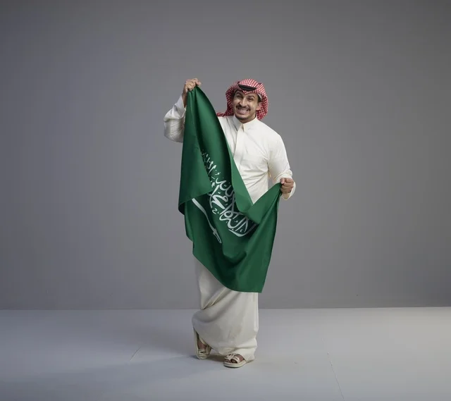 رجل سعودي يحمل العلم السعودي في استوديو