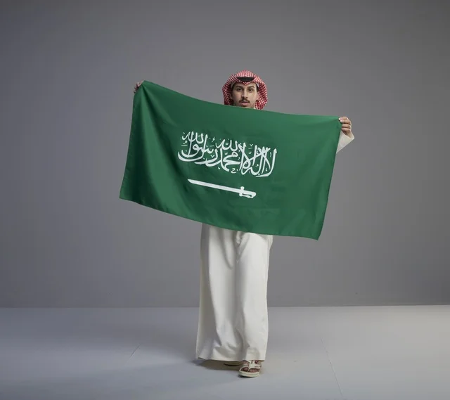 رجل سعودي يحمل العلم الوطني السعودي في الاستوديو
