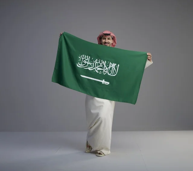 رجل سعودي يحمل علم المملكة العربية السعودية في استوديو