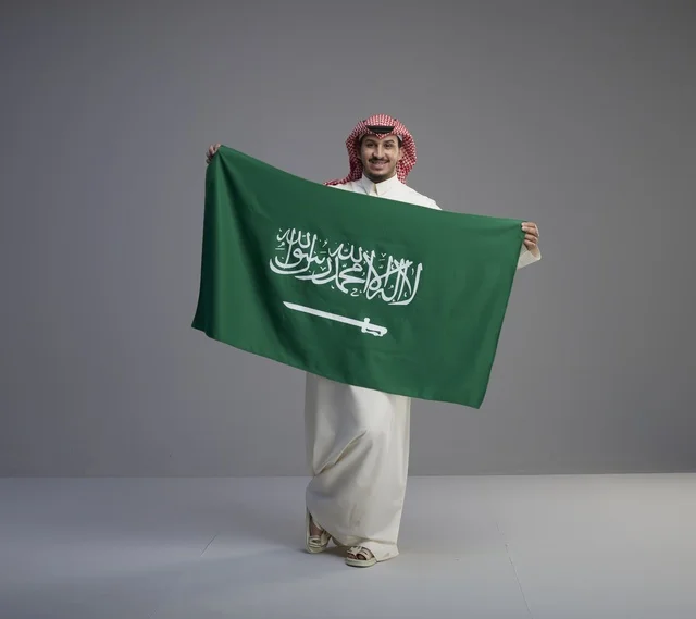 رجل سعودي يحمل العلم الوطني السعودي في الاستوديو