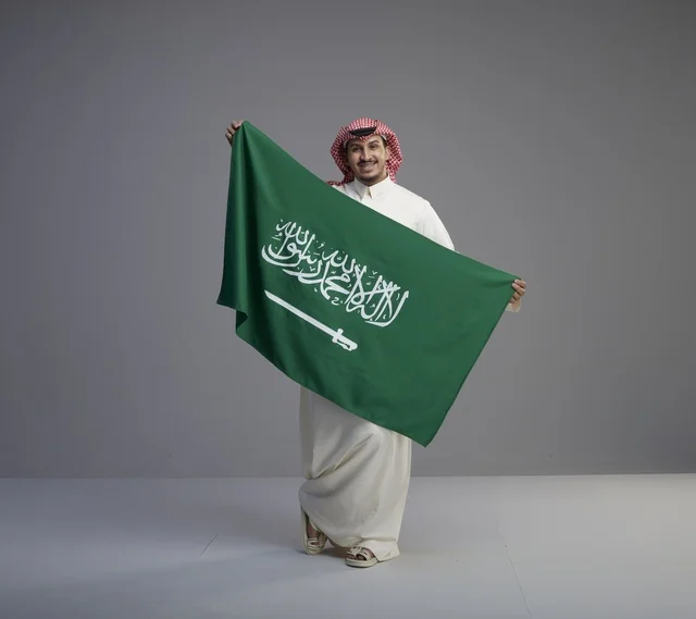 رجل سعودي يحمل علم المملكة العربية السعودية في الاستوديو